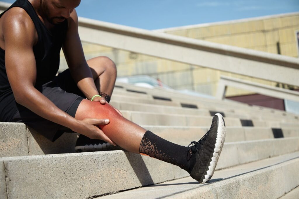 An athlete holding their knee as they experience knee pain from running.